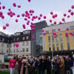 Zebrane przed budynkiem BCO osoby wypuszczają balony w górę.