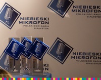 Statuetki Niebieski mikrofon stojące na tle ścianki z napisami Niebieski Mikrofon