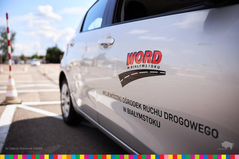 Bok samochodu stojącego  na placu manewrowym. Na drzwiach logo WORD Białystok.