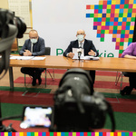 Marszałek Kosicki i Paweł Jungerman, skarbnik województwa, siedzą w maskach przy stole prezydialnym. Na pierwszym planie aparaty fotograficzne