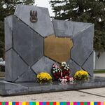 Pomnik z mapą Polski. Przed pomnikiem stoją kwiaty oraz wieńce
