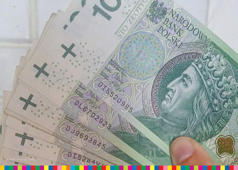 Kilka stuzłotowych polskich banknotów trzymanych w ręku