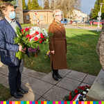 Mężczyzna składający kwiaty przy pomniku. Obok niego stoi kobieta. 