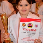 Młoda zawodniczka karate pozuje do zdjęcia z pucharem i dyplomem