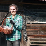 Kobieta z koszykiem w rękach przed drewnianym obiektem