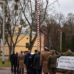 Osoby uczestniczące w zaprzysiężeniu stoją przed polską flagą