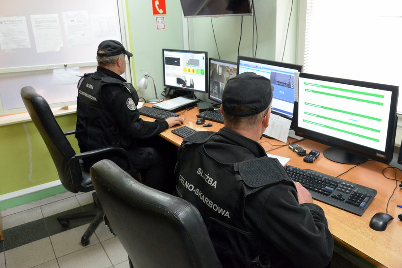 Dwóch funkcjonariuszy KAS siedzi przy stanowiskach komputerowych