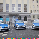 Trzy radiowozy policyjne zaparkowane przed budynkiem Komendy Wojewódzkiej Policji w Białymstoku.