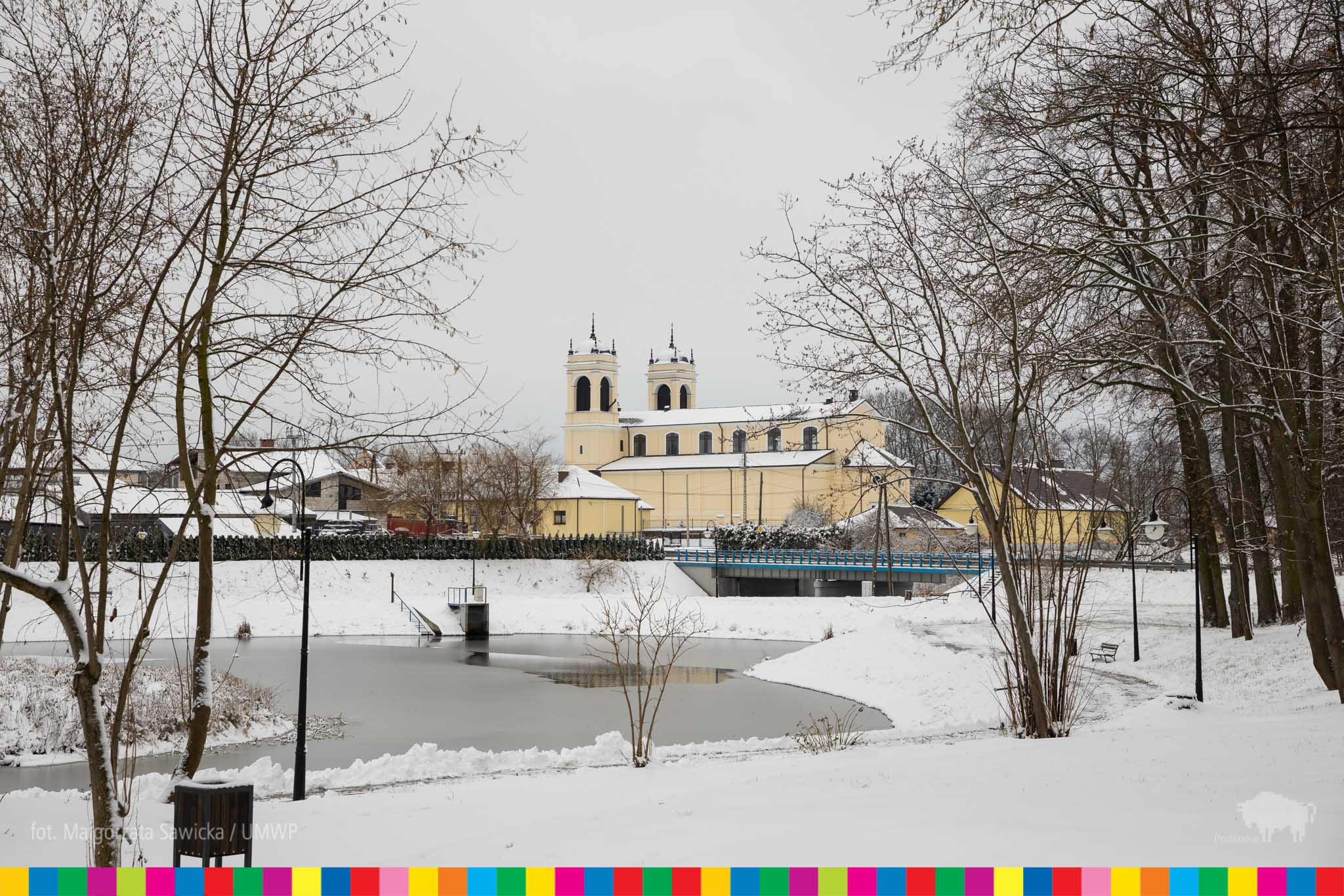 Zimowy krajobraz Czyżewa. Na pierwszym planie widać rzekę, na drugim kościół.