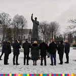 Grupa osób stoi przed pomnikiem księdza Jerzego Popiełuszki
