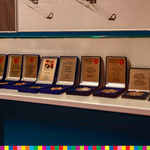 Rząd replik medali olimpijskich w ozdobnych pudełkach.