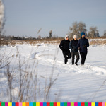 Trzy osoby biegnące po zaśnieżonej łące