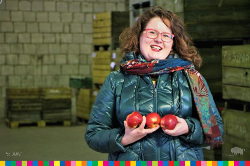 Kobieta trzyma w dłoniach kilka czerwonych jabłek