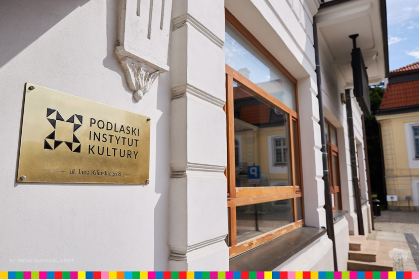 Wejście do siedziby głównej Podlaskiego Instytutu Kultury. Na pierwszym planie tablica informacyjna z nazwą instytucji.