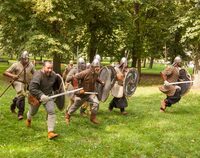 Mężczyźni przebrani za średniowiecznych wojów w natarciu.