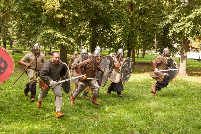 Mężczyźni przebrani za średniowiecznych wojów w natarciu.
