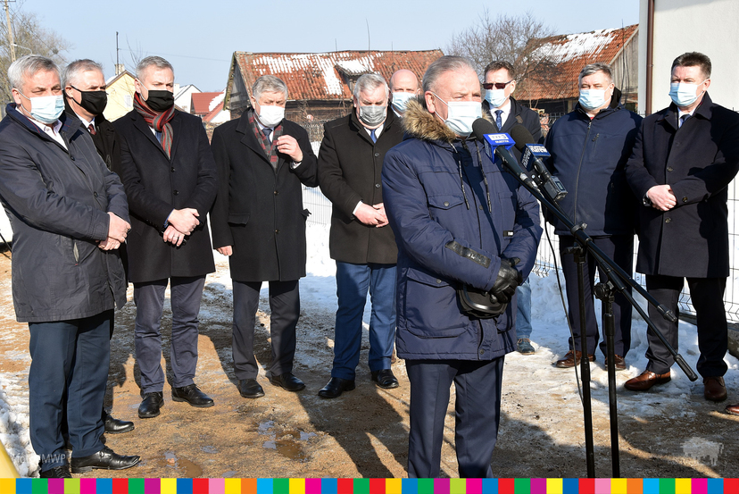 Grupa mężczyzna w maskach. Na pierwszym planie wicemarszałek Marek Olbryś mówi do mikrofonu