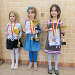Trzy dziewczynki stoją z dyplomami i pucharami