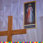 Z lewej strony widoczna górna część krzyża. Z prawej u góry wiszący obraz Jezusa Miłosiernego