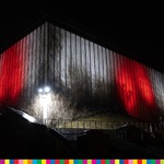 Fragment budynku Opery i Filharmonii Podlaskiej oświetlony w biało-czerwono-białych barwach.