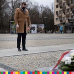 Dyr. Jabłoński z pochyloną głową przed pomnikiem Jana Pawła II.