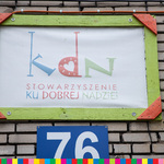 Tabliczka na ścianie budynku z logo Stowarzyszenia Ku Dobrej Nadziei