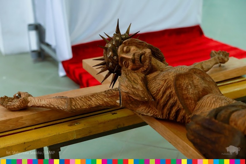 Fragment leżącego drewnianego krzyża z Jezusem.