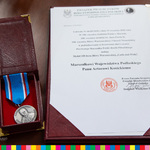 Po lewej medal w ozdobnym pudełku. Po prawej treść uchwały o przyznaniu go marszałkowi.