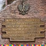 Tablica umieszczona na kamieniu. U góry nad napisem jest polskie godło