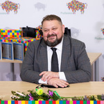 Uśmiechnięty wicemarszałek Stanisław Derehajło siedzi za stołem