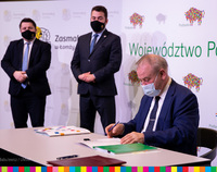 Wicemarszałek Marek Olbryś podpisuje umowę, w tle stoją prezydent oraz wiceprezydent Łomży