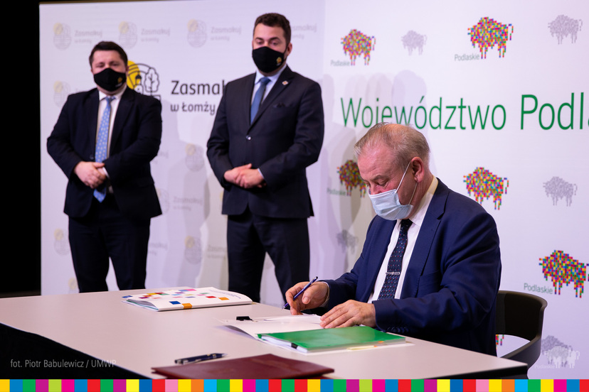 Wicemarszałek Marek Olbryś podpisuje umowę, w tle stoją prezydent oraz wiceprezydent Łomży