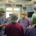 Kilkoro lekarzy w fartuchach lekarskich rozmawia na sali operacyjnej