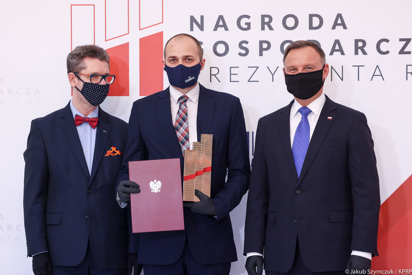 Trzech mężczyzn: Prezydent Andrzej Duda, pierwszy z prawej, z wicedyrektorem firmy Suempol (w środku), trzymającym otrzymane wyróżnienie.