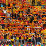 Kibice w strojach czerwono-żółtych trzymają szaliki klubu Jagiellonia