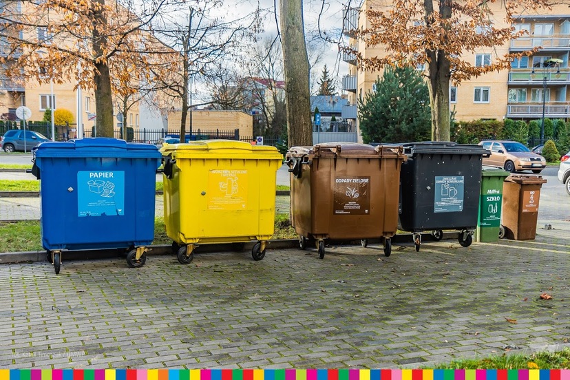 Kubły do segregacji śmieci: niebieski, żółty, brązowy i czarny ustawione w rzędzie.