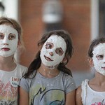 Trzy dziewczynki z białymi maskami na twarzach.