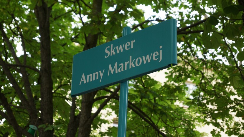 Na tle drzew tabliczka z napisem: Skwer Anny Markowej.
