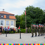 Na placu stoją żołnierze, poczty sztandarowe oraz maszt z flagą biało-czerwoną