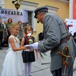 Dziewczynki wręczają kwiaty mężczyźnie przebranemu za Józefa Piłsudskiego
