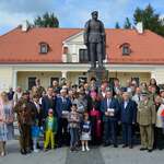 Uczestnicy wydarzenia pozują do zdjęcia pod pomnikiem Józefa Piłsudskiego 