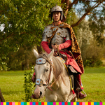 Mężczyzna ubrany w zbroi siedzi na białym koniu