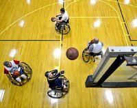 Osoby na wózkach inwalidzkich rzucają piłkę do kosza