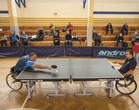 Dwaj zawodnicy na wózkach grają w tenisa stołowego.