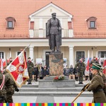 Wojskowe poczty sztandarowe maszerują przed pomnikiem Józefa Piłsudskiego