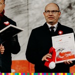 Marszałek Kosicki uśmiecha się i trzyma w ręku dyplom i biało-czerwoną czapkę