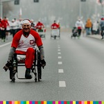 Mężczyzna przemieszcza się na wózku inwalidzkim i również rywalizuje w biegu