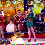 Wokalistka Cleo występuje w kolorowym stroju na scenie w towarzystwie ubranych na czerwono kobiet