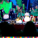 Maja Hyży śpiewa na scenie w towarzystwie Pań ubranych na zielono oraz mężczyzn ubranych w smokingi i muszki