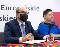 Marszałek Artur Kosicki siedzi za biurkiem z długopisem wraz z Joanną Sarosiek, dyrektor Departamentu Rozwoju Regionalnego